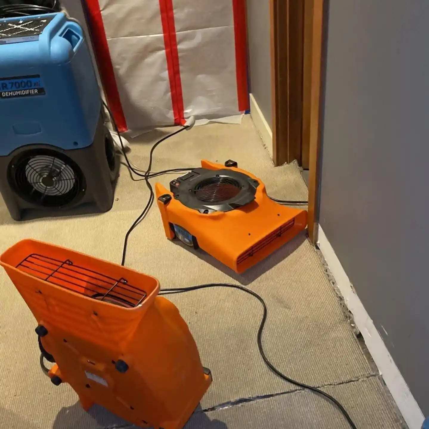 Dehumidifier and air movers at a plastic containment wall in a hallway