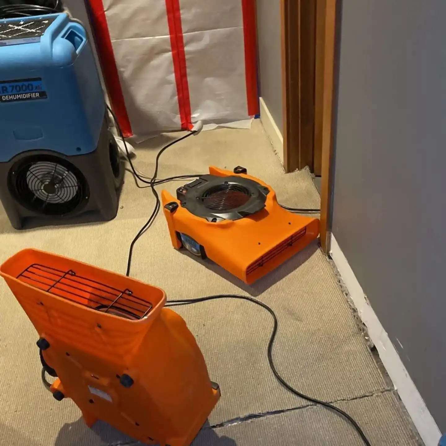Dehumidifier and air movers at a plastic containment wall in a hallway